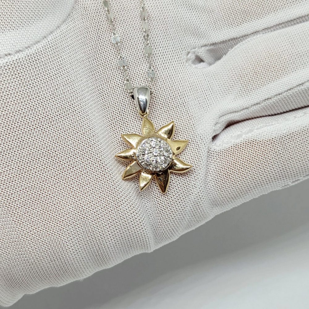 collana oro giallo e bianco 18k, ciondolo a forma di sole con pietrine centrali su sfondo bianco