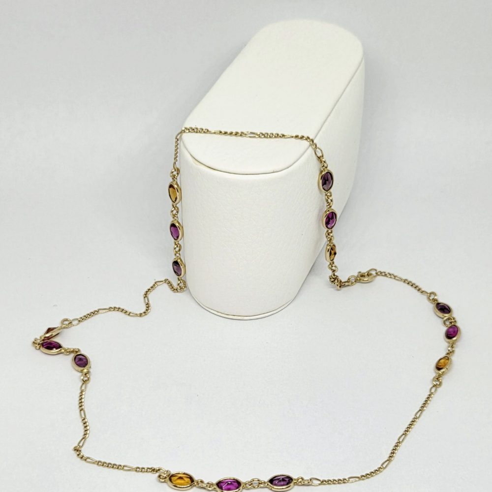 collana oro giallo 18k con pietrine blu,rosa e gialle su sfondo bianco