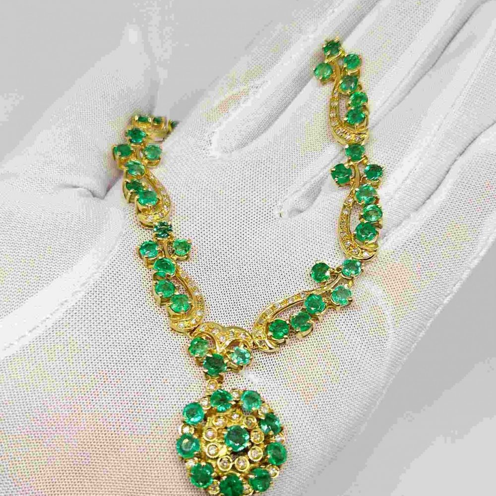 Collana lavorata oro giallo 18k con smeraldi e diamanti su sfondo bianco